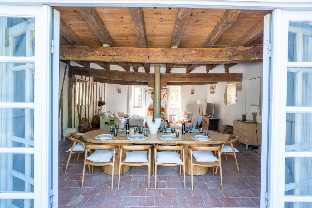 Salon, 6.8x10m, with massive beamed ceiling, terracotta floor, Vigilante wood-burning stove beside a central oak pillar, double French windows to courtyard. 