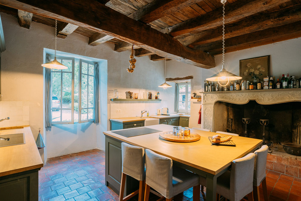 Kitchen, 5x5.2m, with open fireplace, antique 15C carved surround, tiled splashbacks and timber worktops, two porcelain sinks, extensive range of painted cupboards, central island with seating for six.